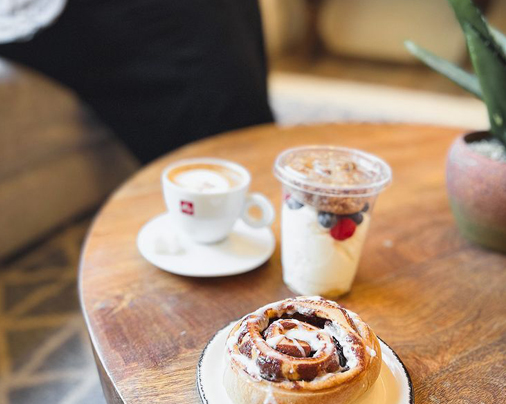 cinnamon bun and a coffee cup placed on a wooden table