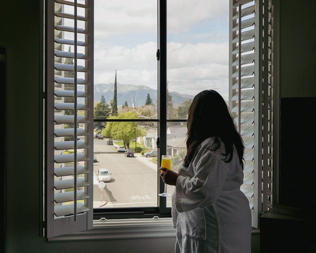 a woman in a bathrobe standing looking out of a window